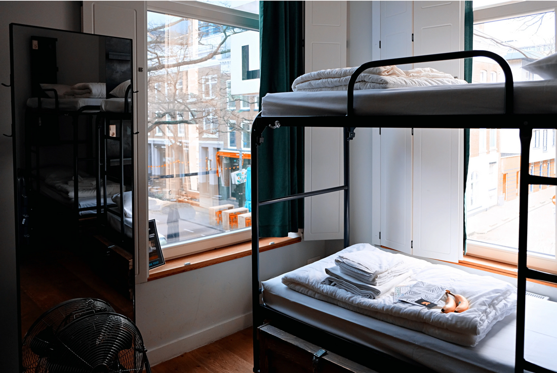 Bunk beds in the corner of a hostel dormitory with folded sheets and bananas on the bottom bunk